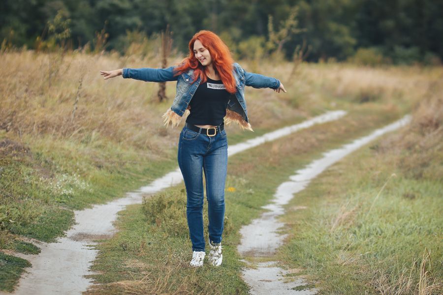 A woman walking happily with open arms along a country path